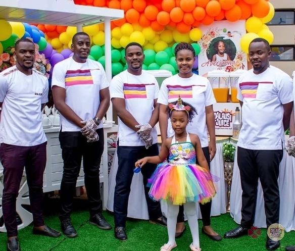 Dalausi team members and a birthday child in front of rainbow balloons