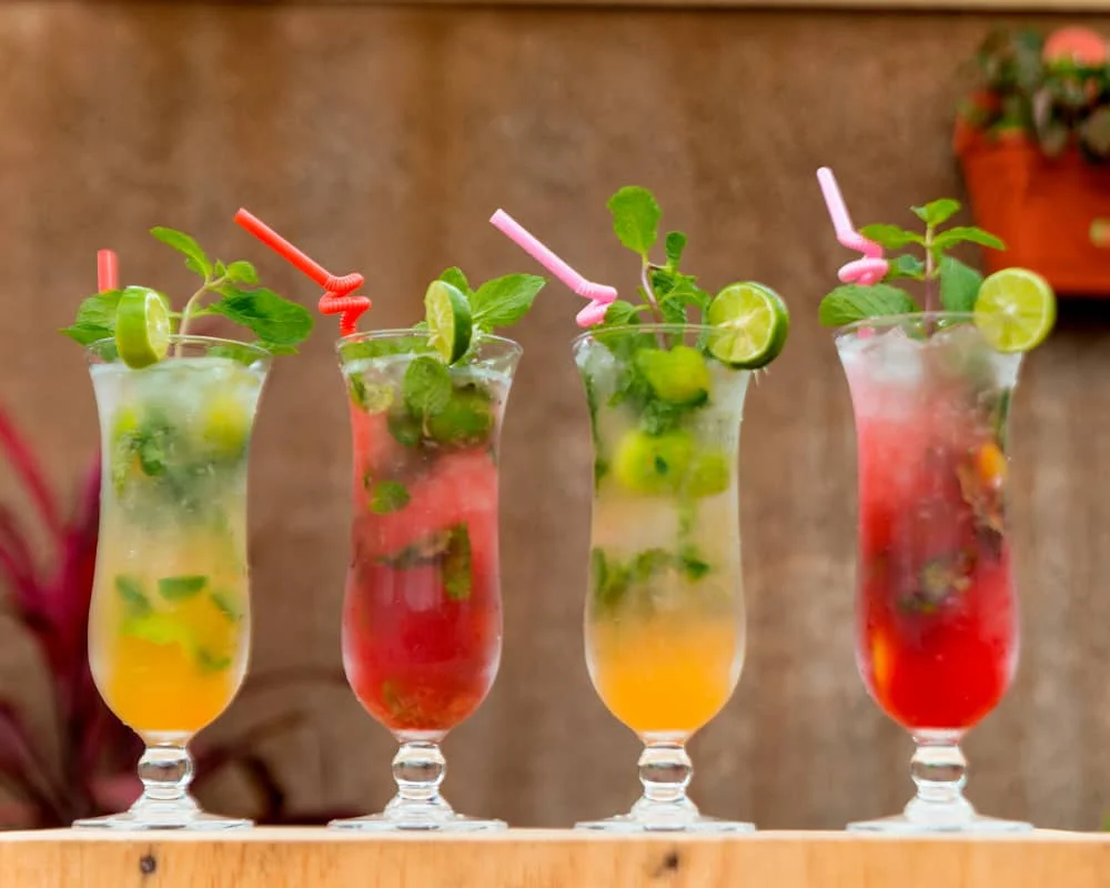 Four colourful mocktails with fresh mint and citrus garnishes