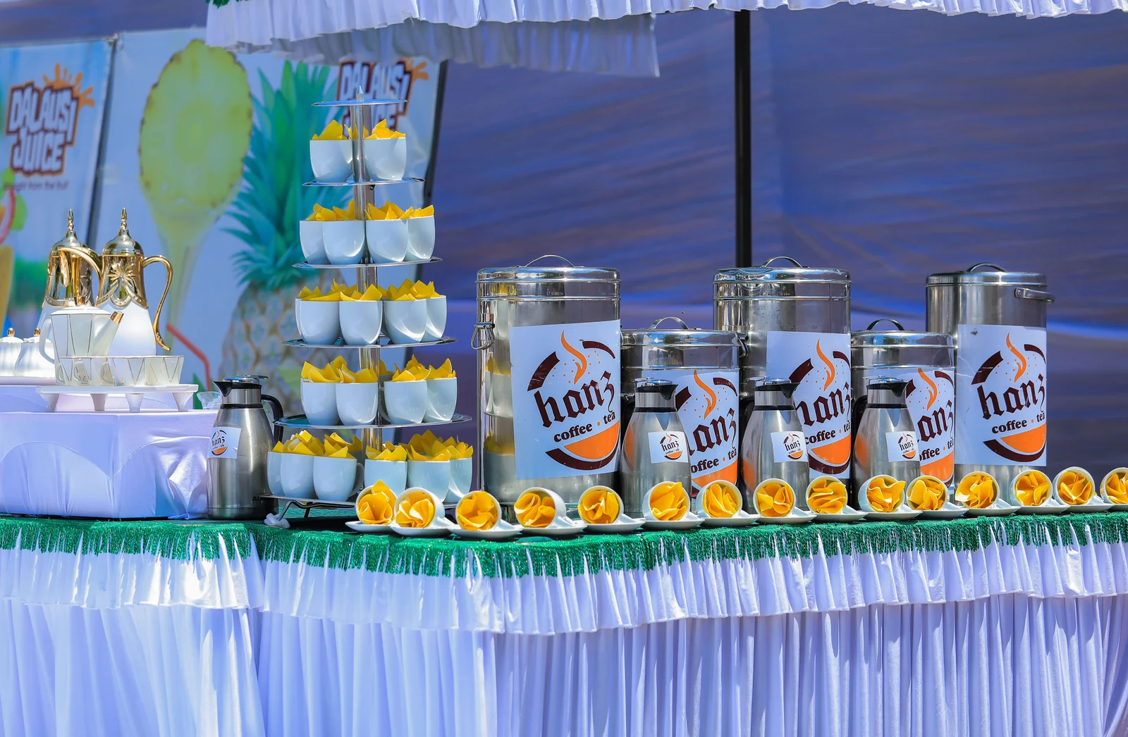 A wedding juice station with dispensers and a tower of glasses