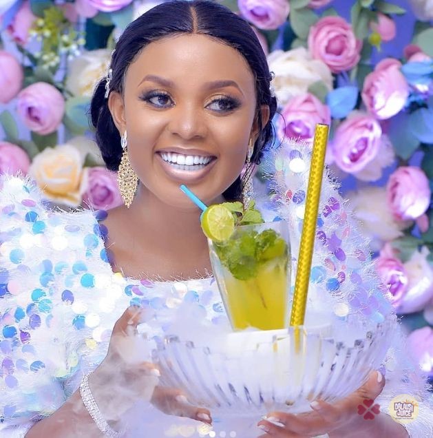A woman in a pale blue introduction outfit holding a mint and lime drink