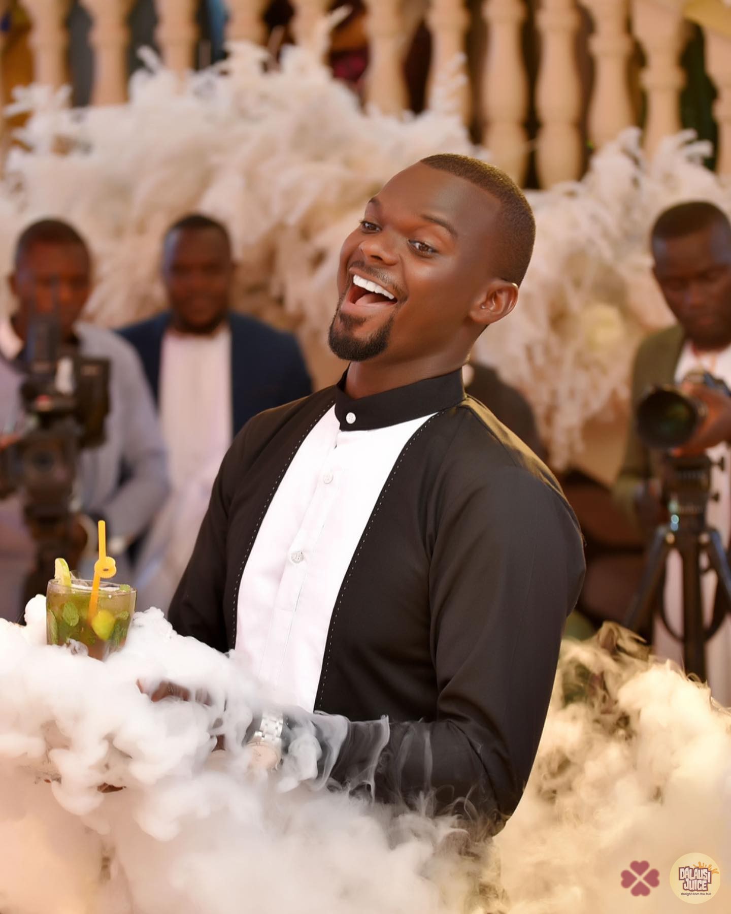 A smiling guest holding a smoky Dalausi drink at a celebration